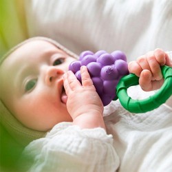 Bébé tenant le hochet anneau de dentition Cerise Oli & Carol en caoutchouc naturel